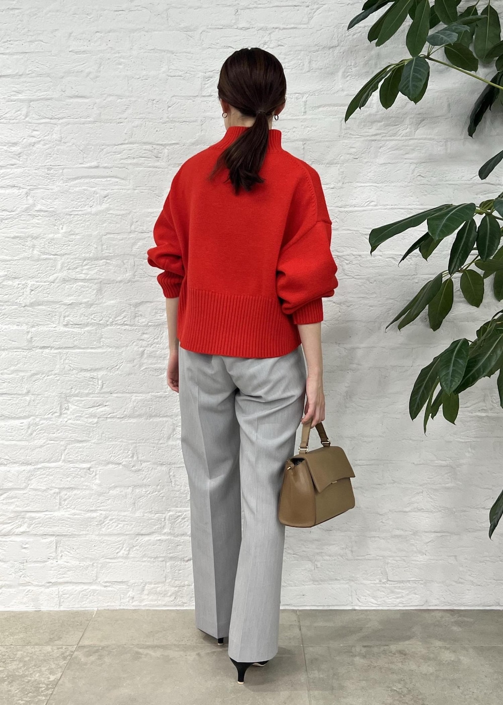 レッド系のニット/セーター、グレー系のその他パンツ、ブラック系のパンプスを着用したレディースの秋コーディネートの3枚目の写真