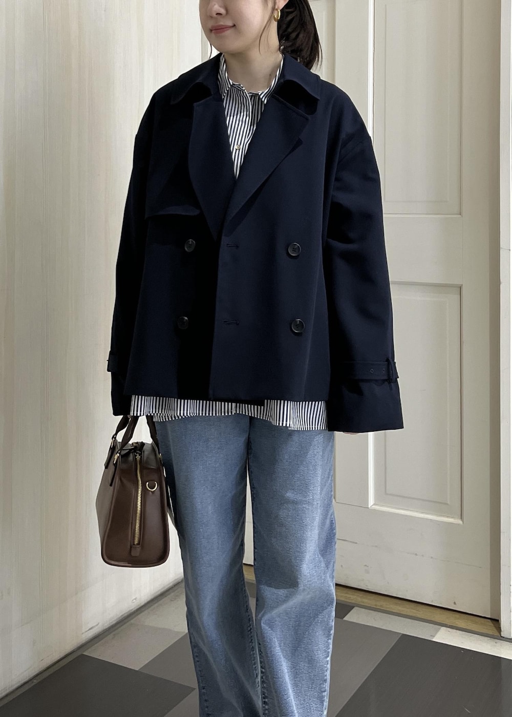 ブラウン系のボストンバッグ、ブルー系のトレンチコート、ブルー系のシャツ/ブラウスを着用したレディースの春コーディネートの5枚目の写真