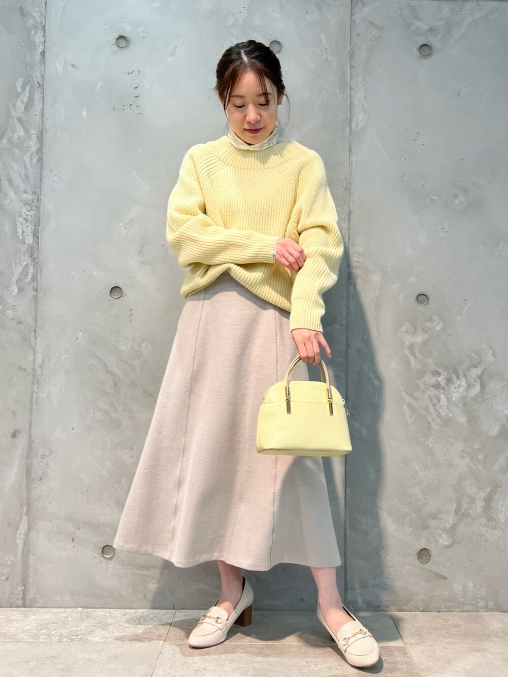 イエロー系のニット/セーター、ピンク系のスカート、イエロー系のボストンバッグを着用したレディースの冬コーディネートの2枚目の写真