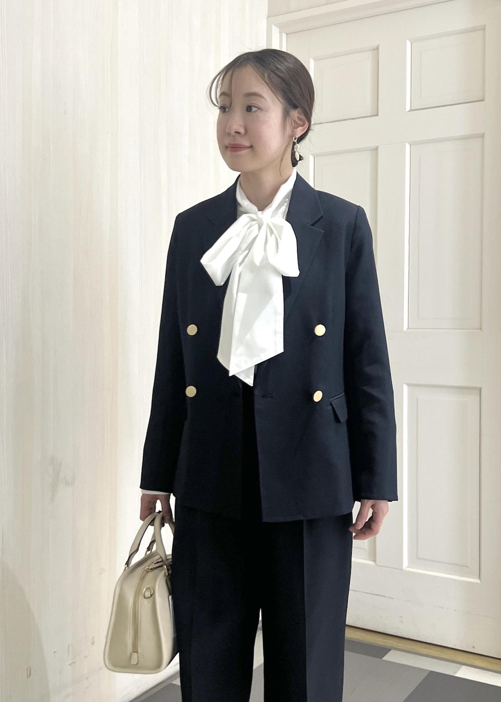 ホワイト系のボストンバッグ、ホワイト系のパンプス、ブルー系のその他パンツを着用したレディースの冬コーディネートの6枚目の写真