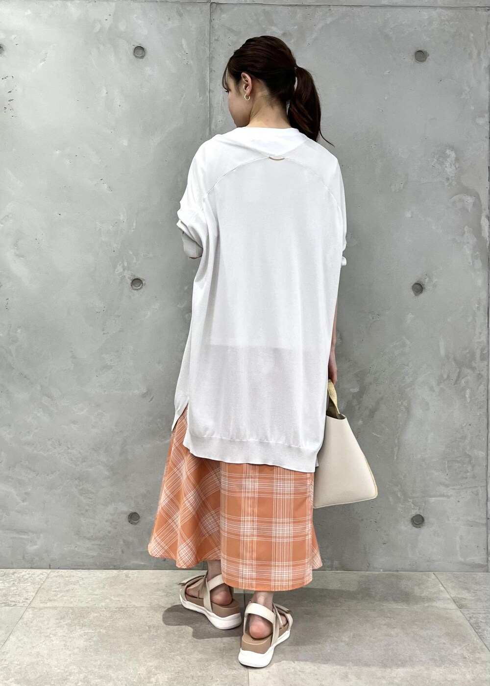 オレンジ系のスカート、グレー系のカーディガン/ボレロ、ホワイト系のTシャツ/カットソーを着用したレディースの春コーディネートの3枚目の写真
