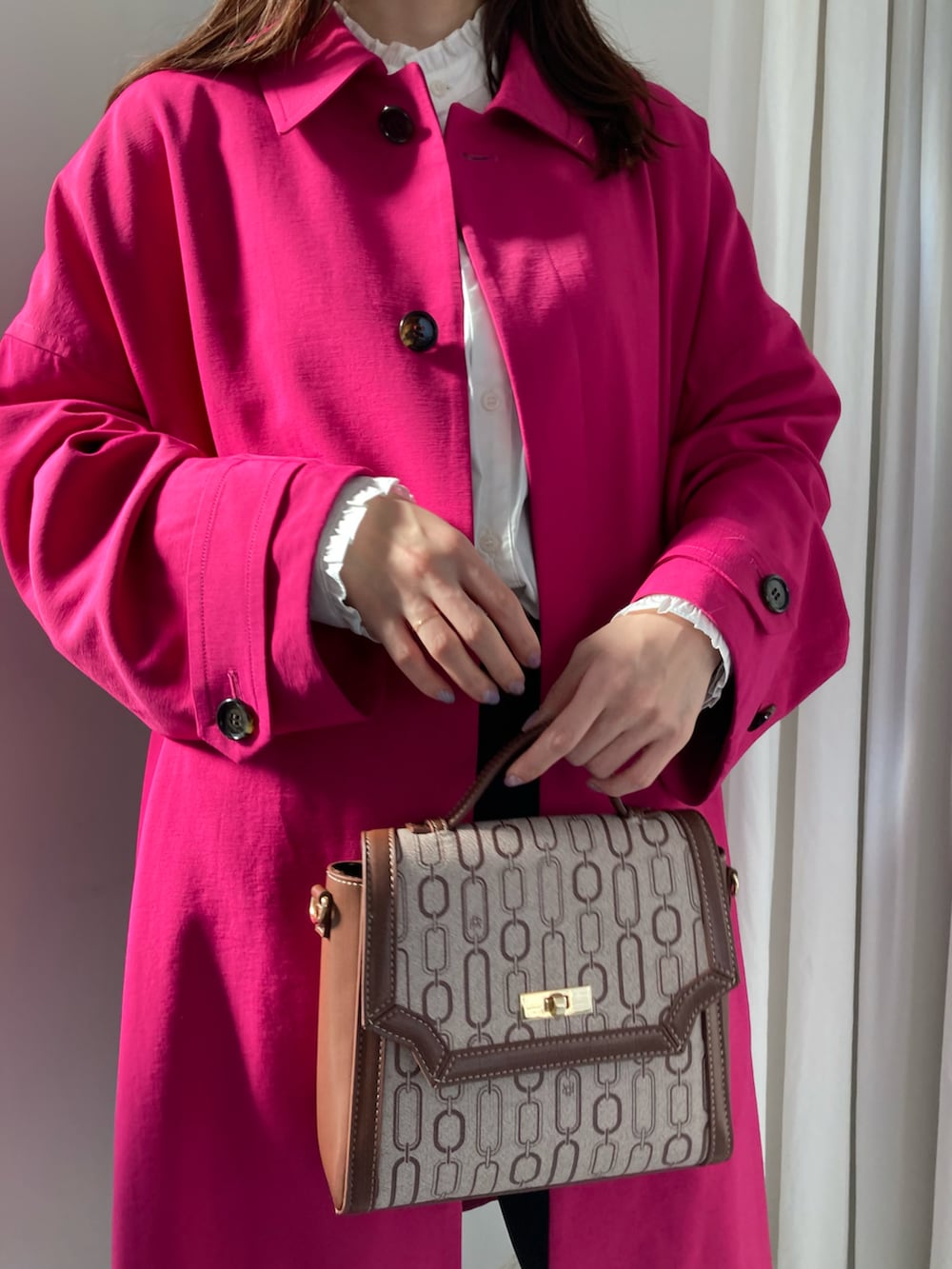 ピンク系のステンカラーコート、ブラウン系のショルダーバッグ、ブラック系のその他パンツを着用したレディースの冬コーディネートの4枚目の写真