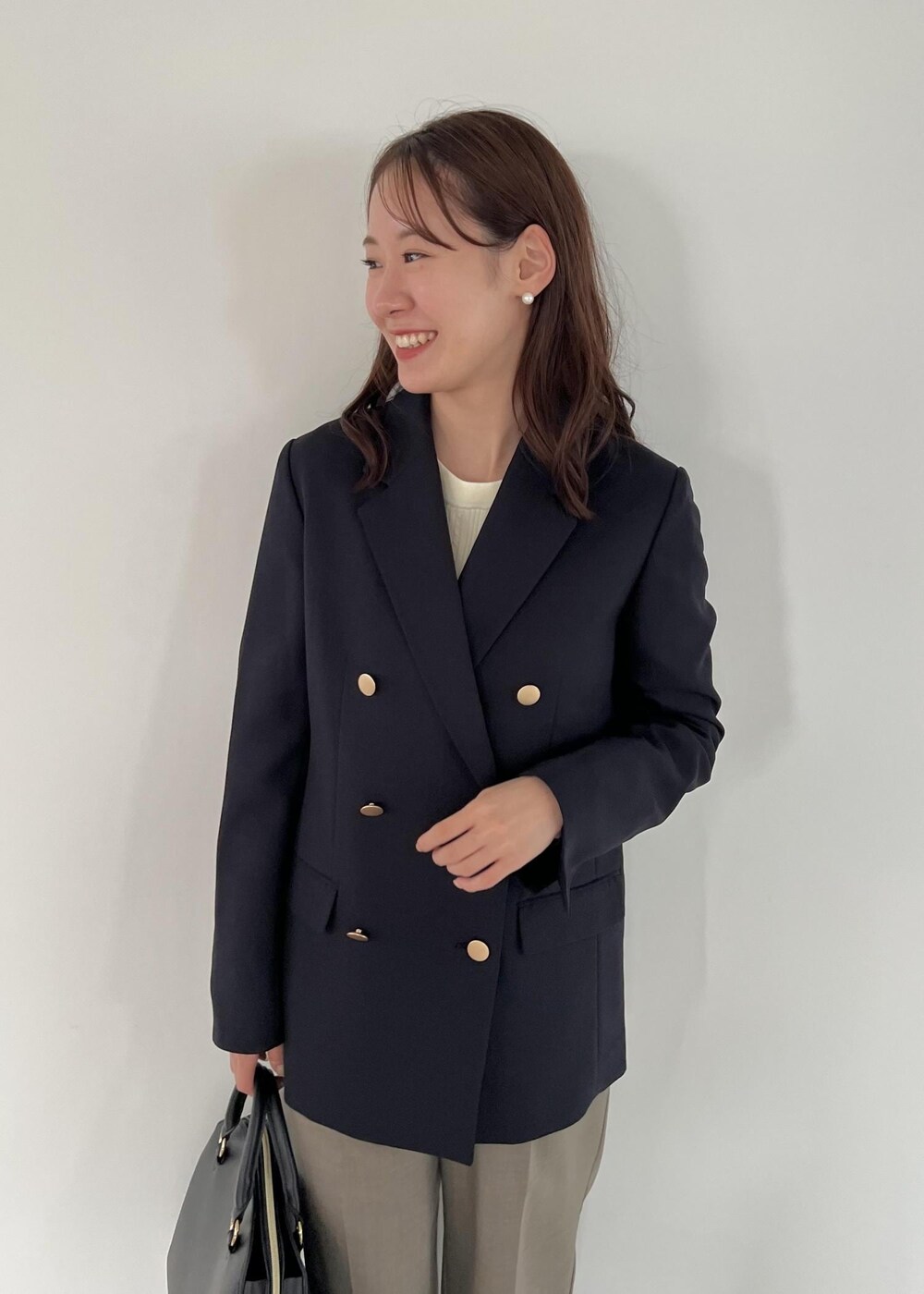 ブラック系のボストンバッグ、ブルー系のテーラードジャケット、ホワイト系のニット/セーターを着用したレディースの秋コーディネートの6枚目の写真