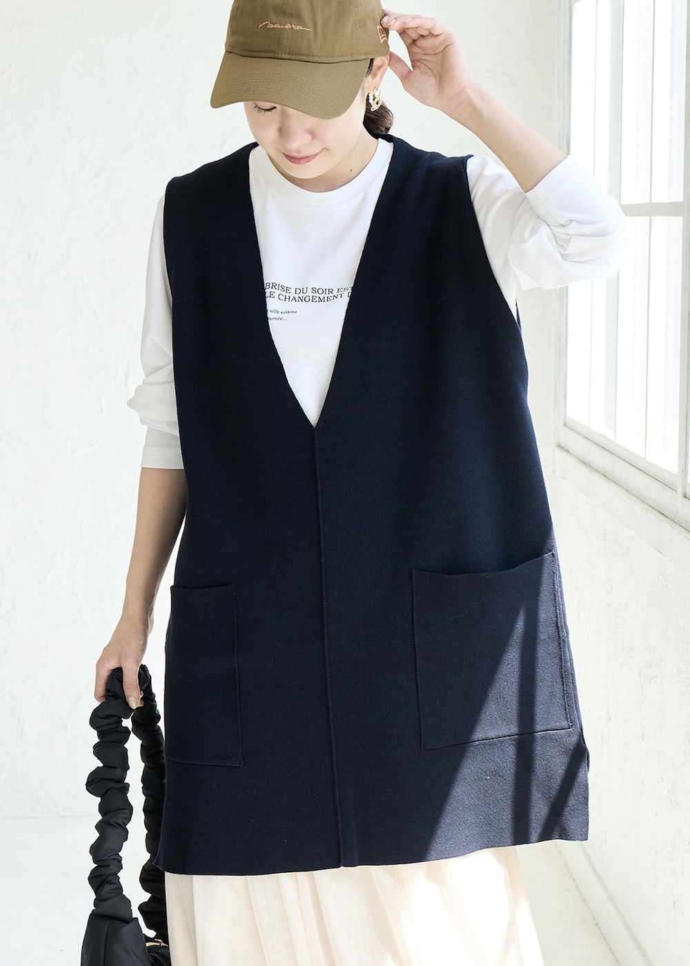 ベージュ系のスカート、ホワイト系のパンプス、ブルー系のベストを着用したレディースの秋コーディネートの4枚目の写真