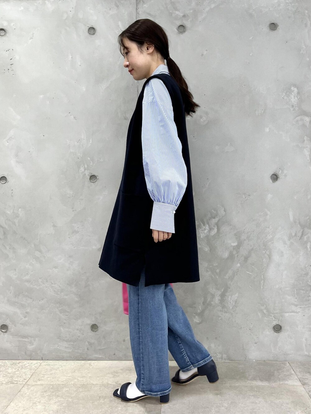 ブルー系のベスト、ブルー系のサンダル、ピンク系のトートバッグを着用したレディースの春コーディネートの2枚目の写真