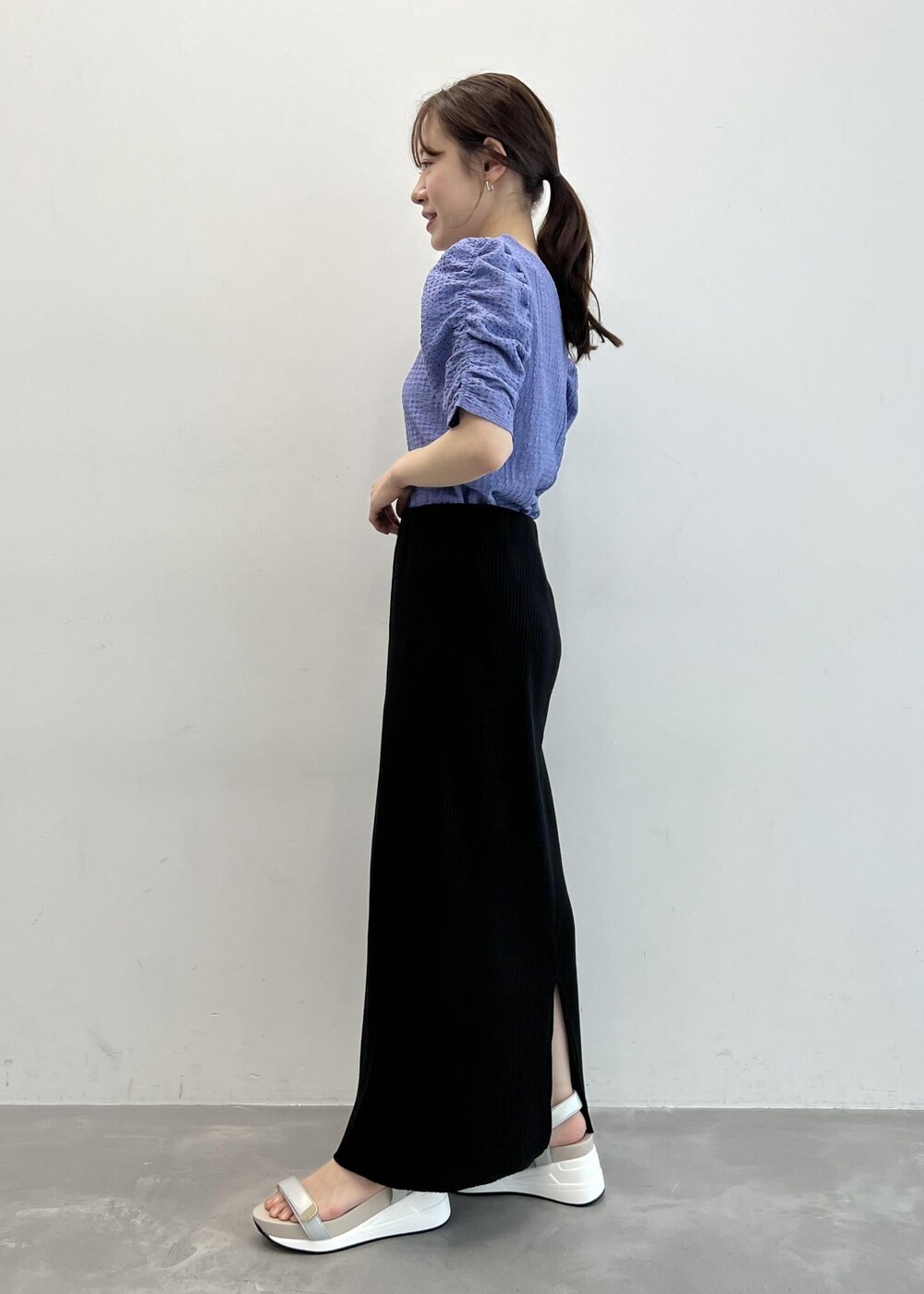 ブラック系のショルダーバッグ、ブルー系のTシャツ/カットソー、ブラック系のスカートを着用したレディースの夏コーディネートの2枚目の写真