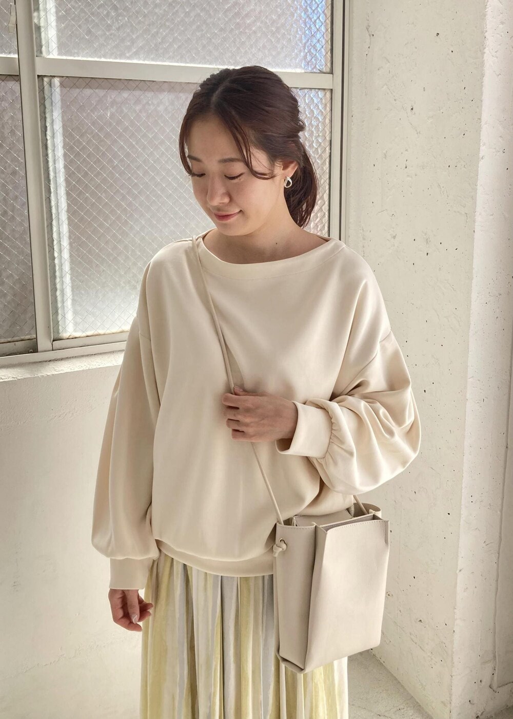 イエロー系のスカート、ホワイト系のニット/セーターを着用したレディースの夏コーディネートの3枚目の写真