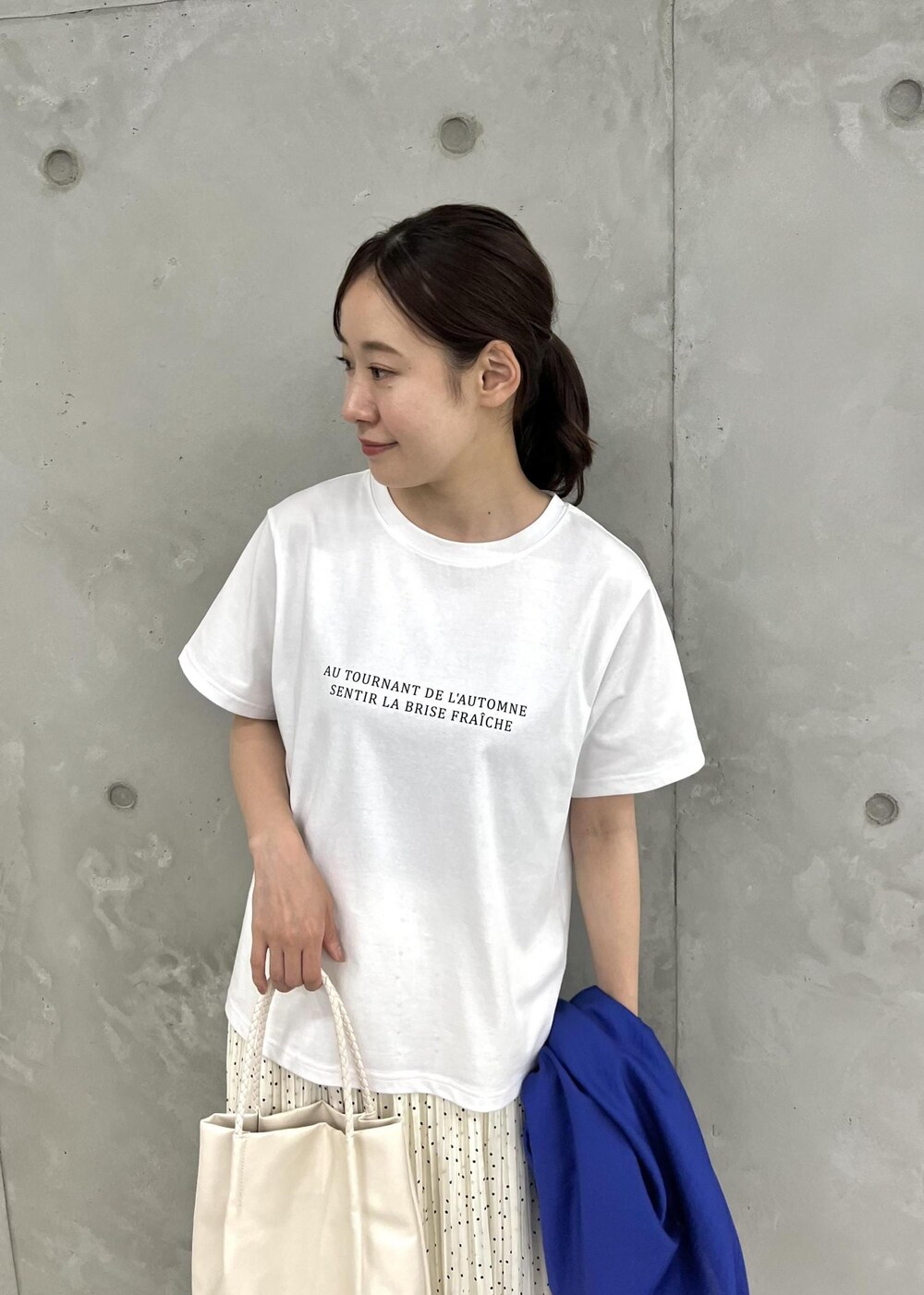 ホワイト系のトートバッグ、ホワイト系のサンダル、ブルー系のシャツ/ブラウスを着用したレディースの夏コーディネートの4枚目の写真