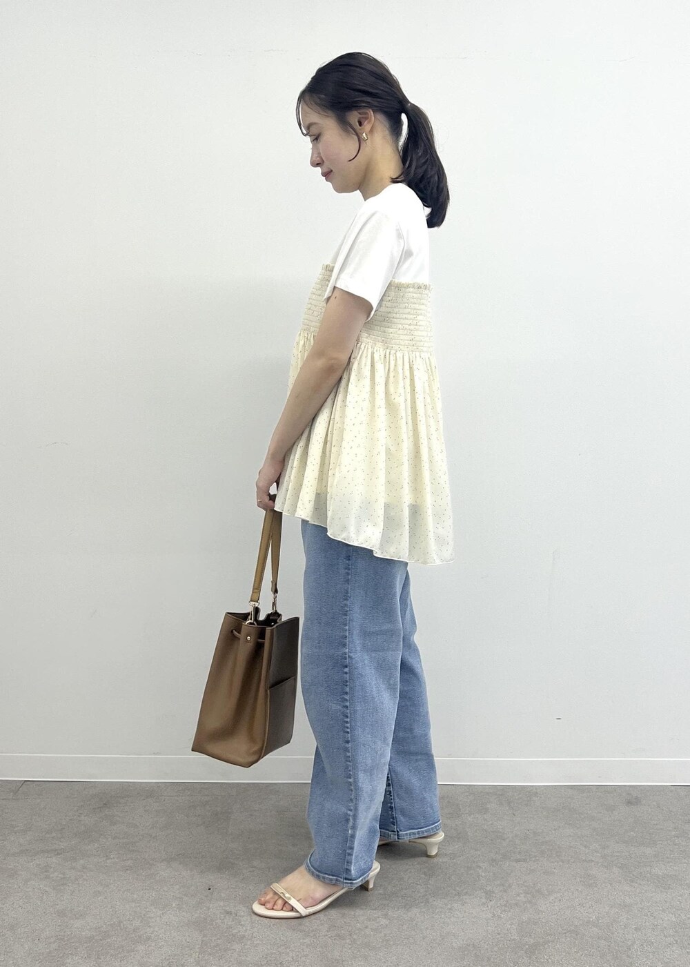 ブルー系のデニムパンツ、ブラウン系のショルダーバッグ、ブラック系のTシャツ/カットソーを着用したレディースの夏コーディネートの2枚目の写真