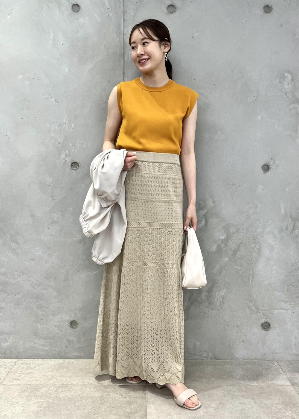 ベージュ系のサンダル、ベージュ系のブルゾン、オレンジ系のニット/セーターを着用したレディースの春コーディネートの4枚目の写真