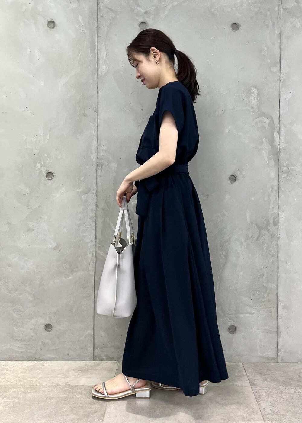 シルバー系のサンダル、ブルー系のワンピース、グレー系のトートバッグを着用したレディースの夏コーディネートの2枚目の写真