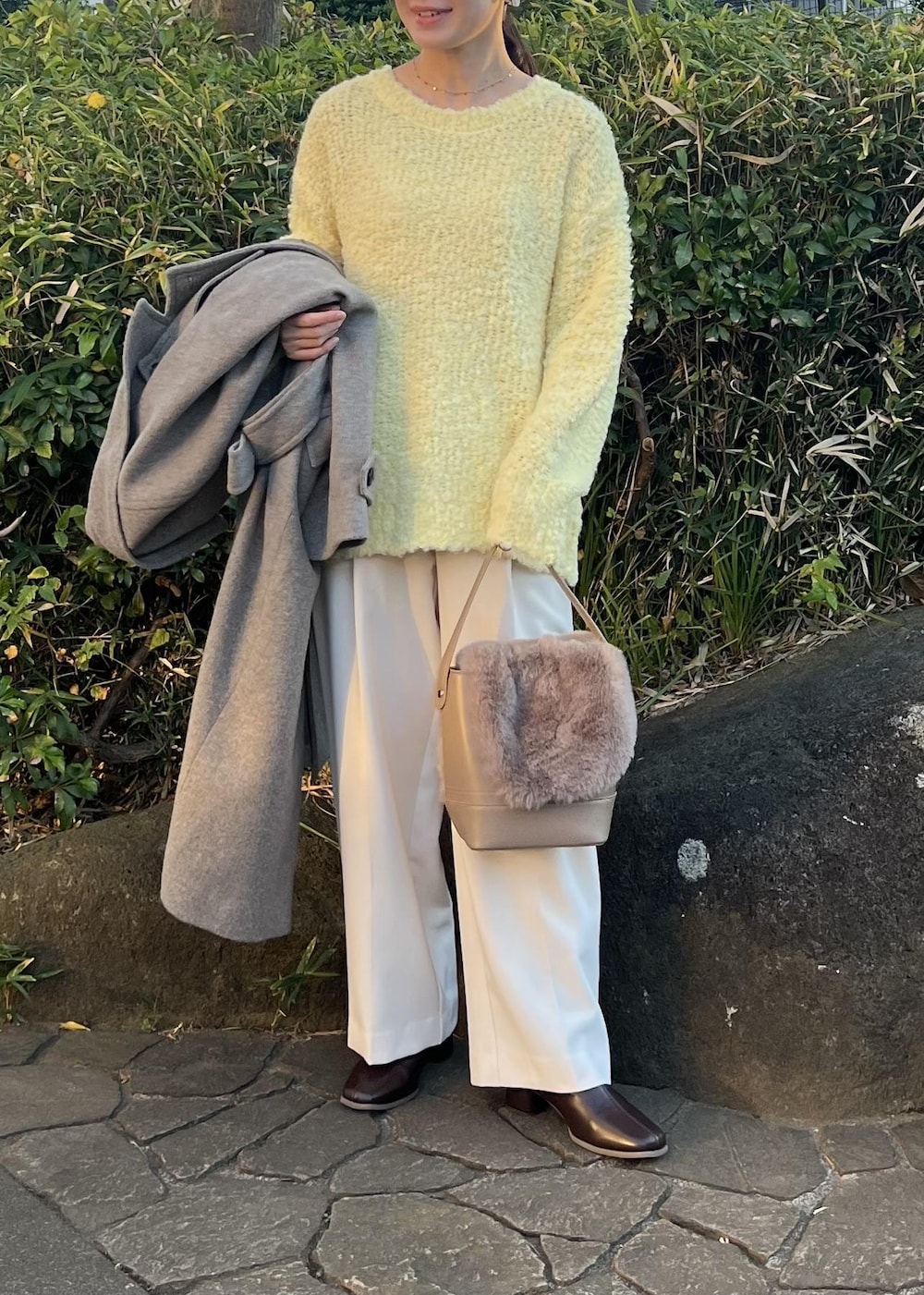 ベージュ系のチェスターコート、ブラウン系のショルダーバッグ、イエロー系のニット/セーターを着用したレディースの秋コーディネートの6枚目の写真