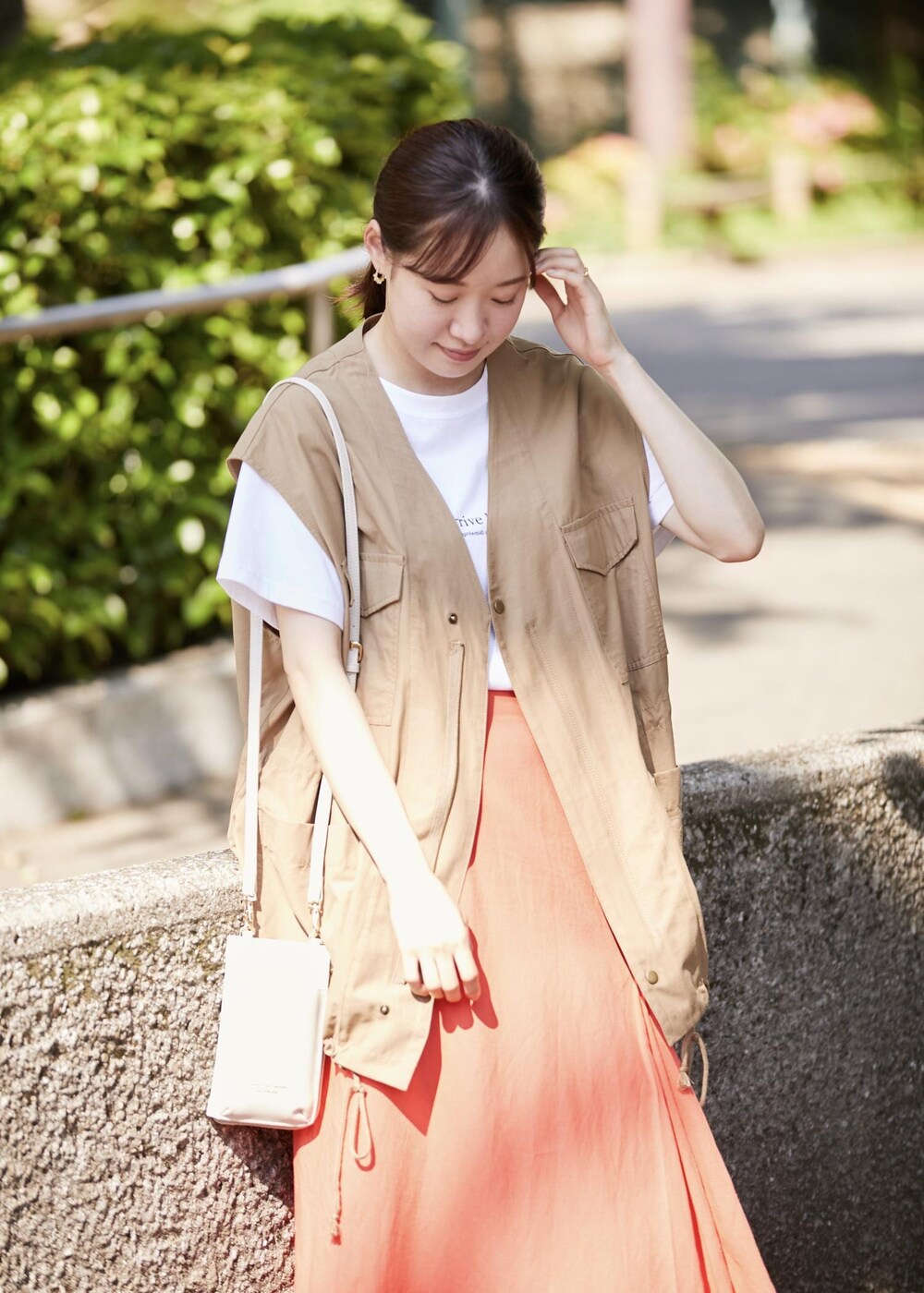 イエロー系のベスト、ホワイト系のショルダーバッグ、ホワイト系のTシャツ/カットソーを着用したレディースの春コーディネートの3枚目の写真