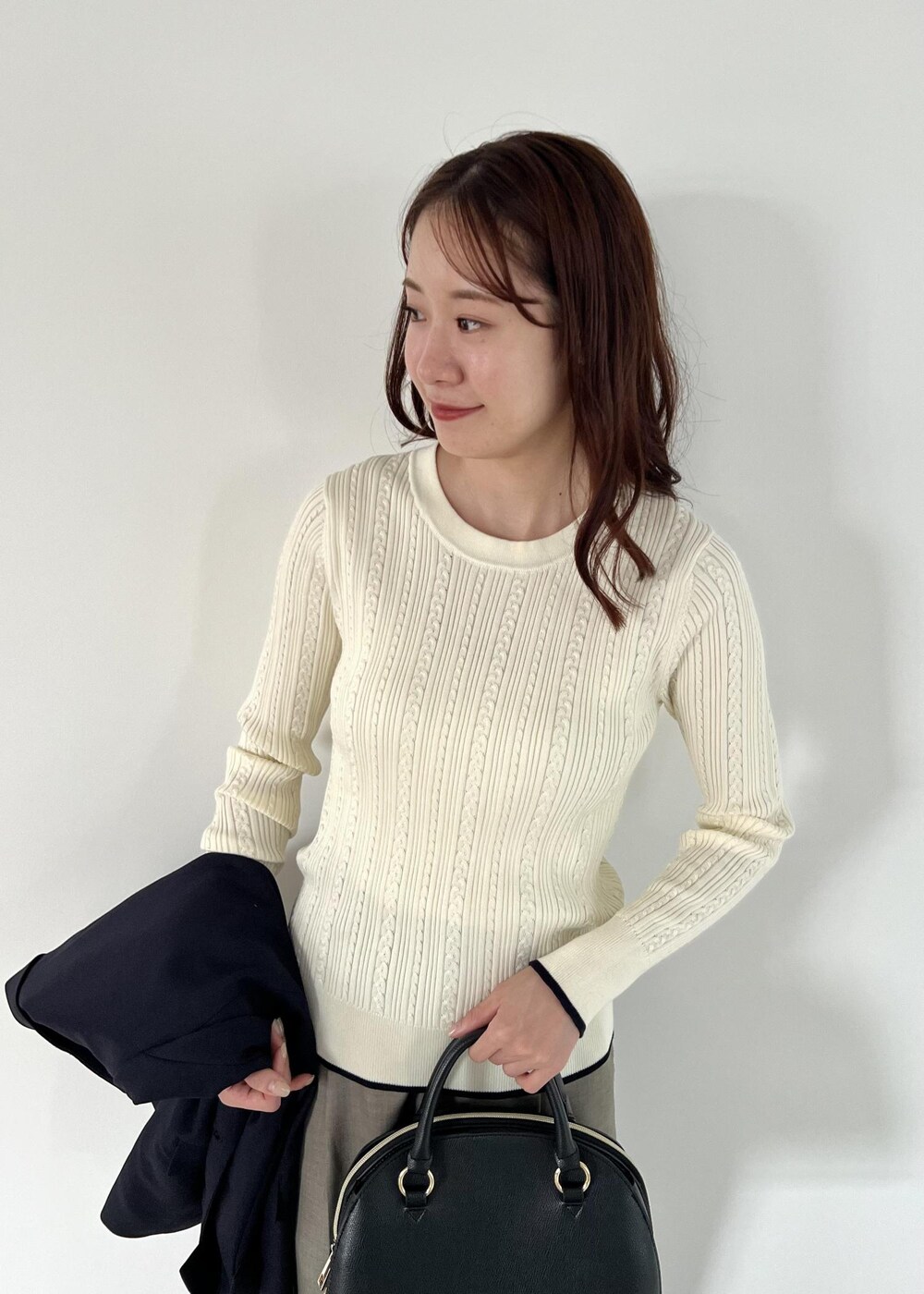 ブラック系のボストンバッグ、ブルー系のテーラードジャケット、ホワイト系のニット/セーターを着用したレディースの秋コーディネートの5枚目の写真