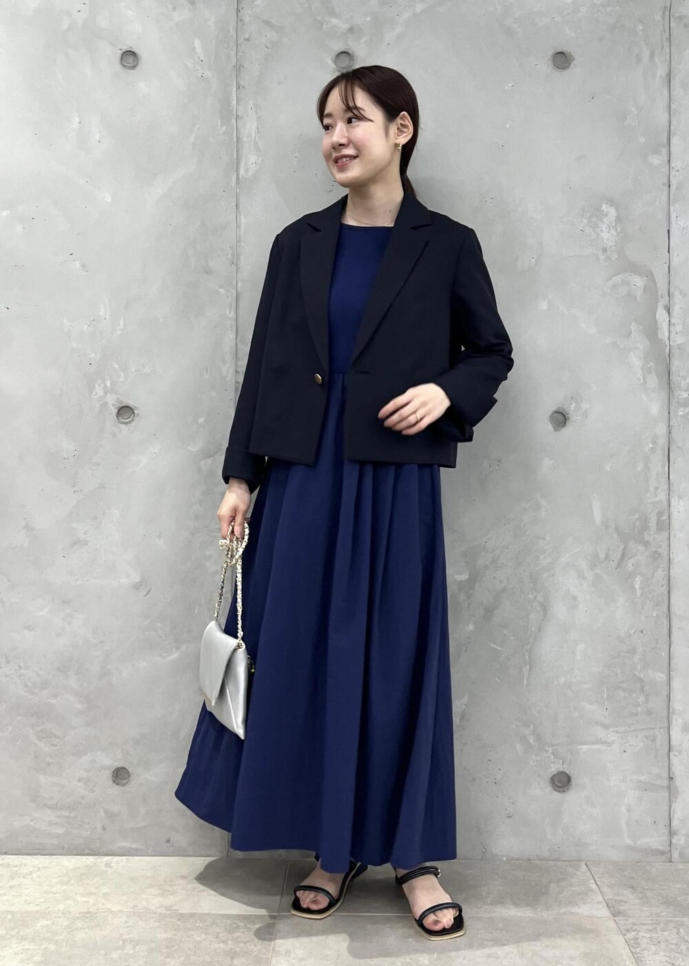 シルバー系のショルダーバッグ、ブラック系のサンダル、ブルー系のテーラードジャケットを着用したレディースの夏コーディネートの4枚目の写真