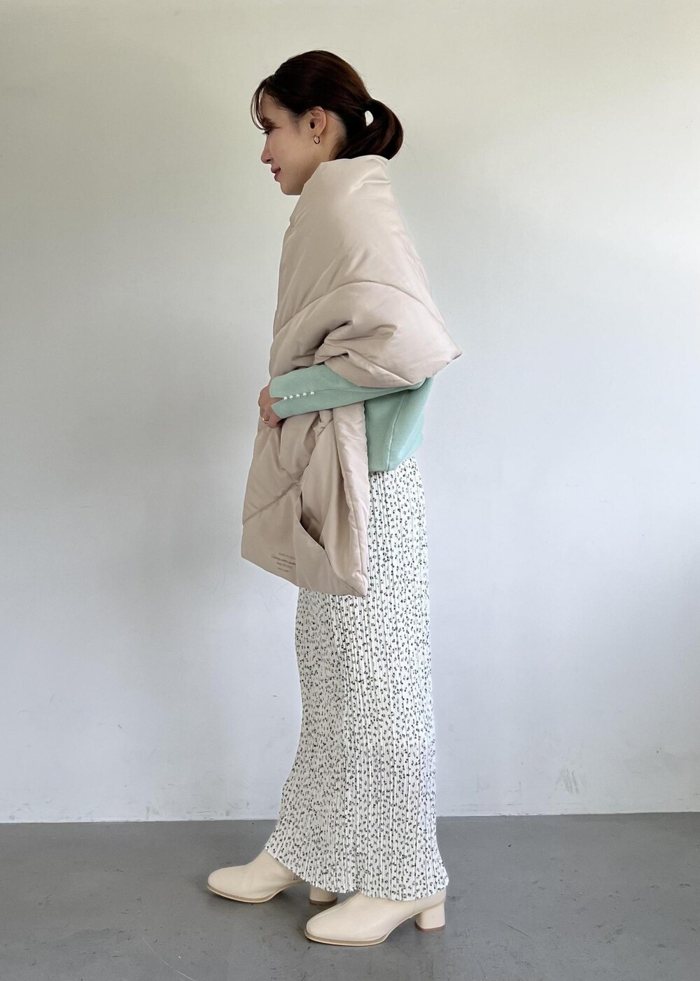 グリーン系のニット/セーター、ホワイト系のブーツ、ホワイト系のスカートを着用したレディースの秋コーディネートの2枚目の写真