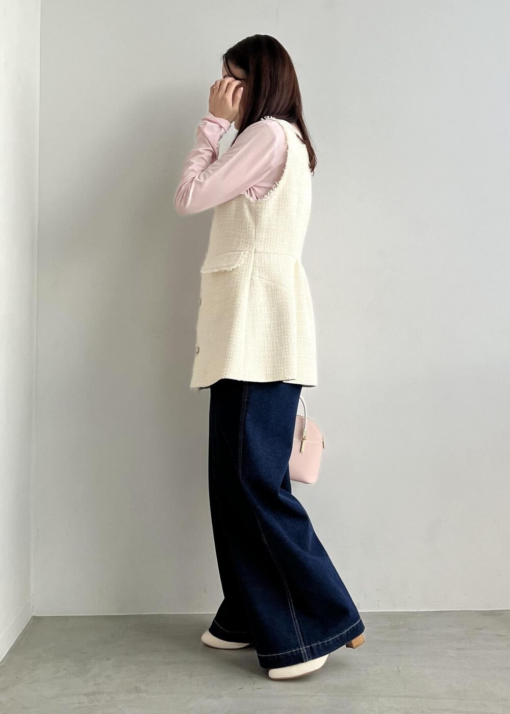 ホワイト系のベスト、ピンク系のTシャツ/カットソー、ブルー系のデニムパンツを着用したレディースの冬コーディネートの2枚目の写真