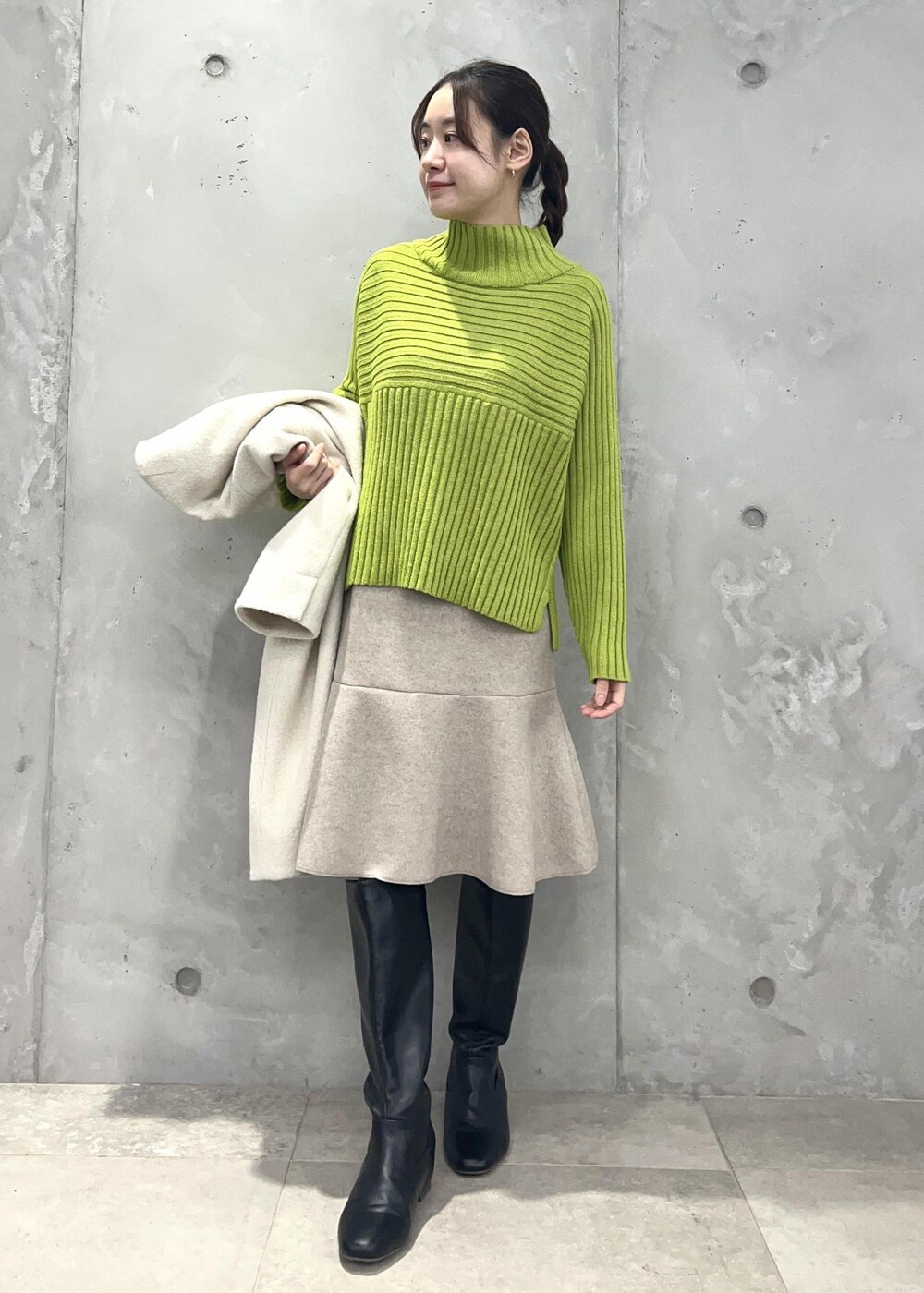 グリーン系のニット/セーター、ベージュ系のスカート、ホワイト系のその他アウターを着用したレディースの冬コーディネートの4枚目の写真