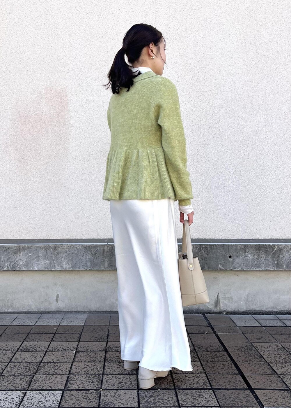 ホワイト系のスカート、グリーン系のニット/セーター、ベージュ系のパンプスを着用したレディースの冬コーディネートの4枚目の写真