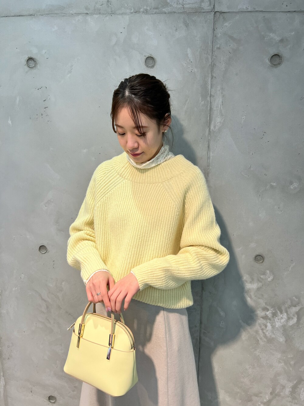 イエロー系のニット/セーター、ピンク系のスカート、イエロー系のボストンバッグを着用したレディースの冬コーディネートの5枚目の写真