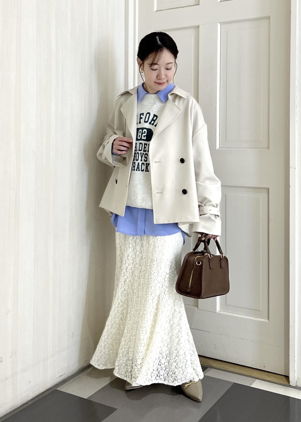 ブラウン系のボストンバッグ、ベージュ系のパンプス、ホワイト系のスウェットを着用したレディースの冬コーディネートの2枚目の写真