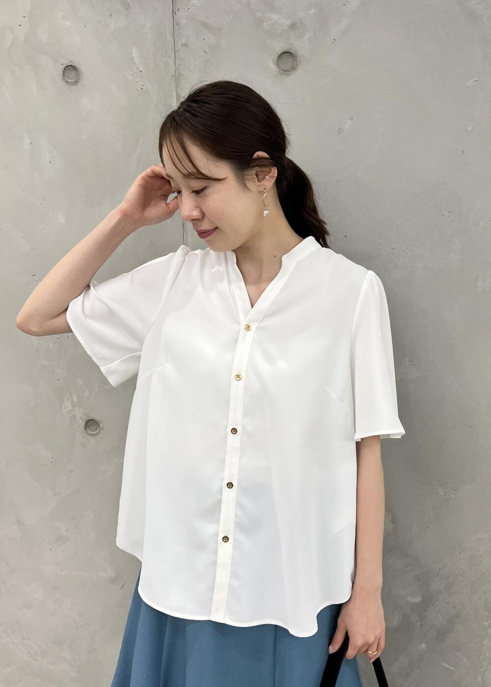 ブラック系のパンプス、ブルー系のスカート、ブラック系のショルダーバッグを着用したレディースの春コーディネートの5枚目の写真