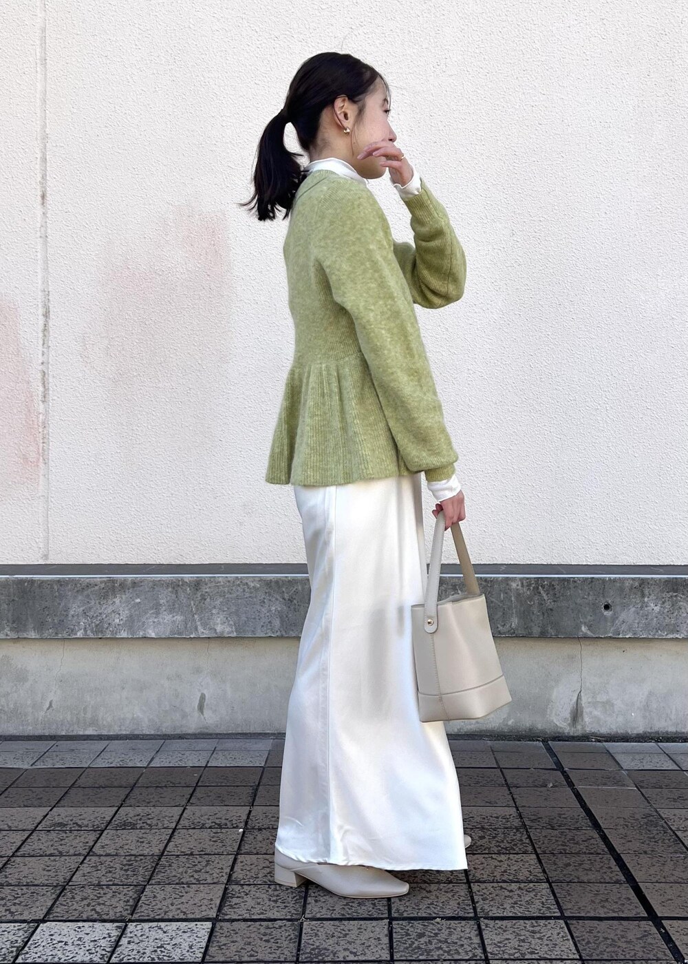 ホワイト系のスカート、グリーン系のニット/セーター、ベージュ系のパンプスを着用したレディースの冬コーディネートの5枚目の写真