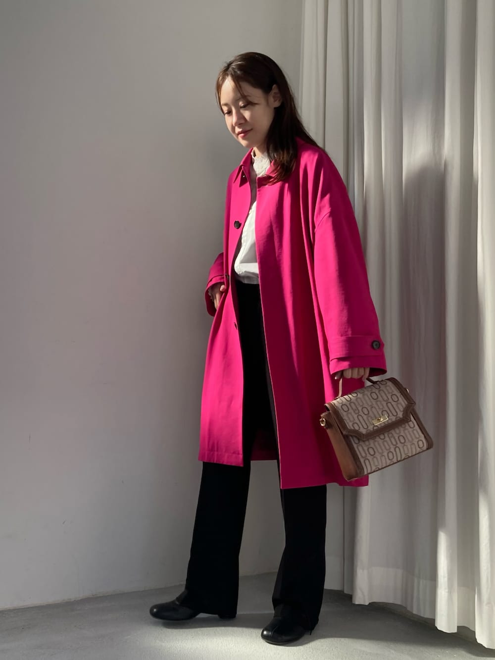 ピンク系のステンカラーコート、ブラウン系のショルダーバッグ、ブラック系のその他パンツを着用したレディースの冬コーディネートの2枚目の写真