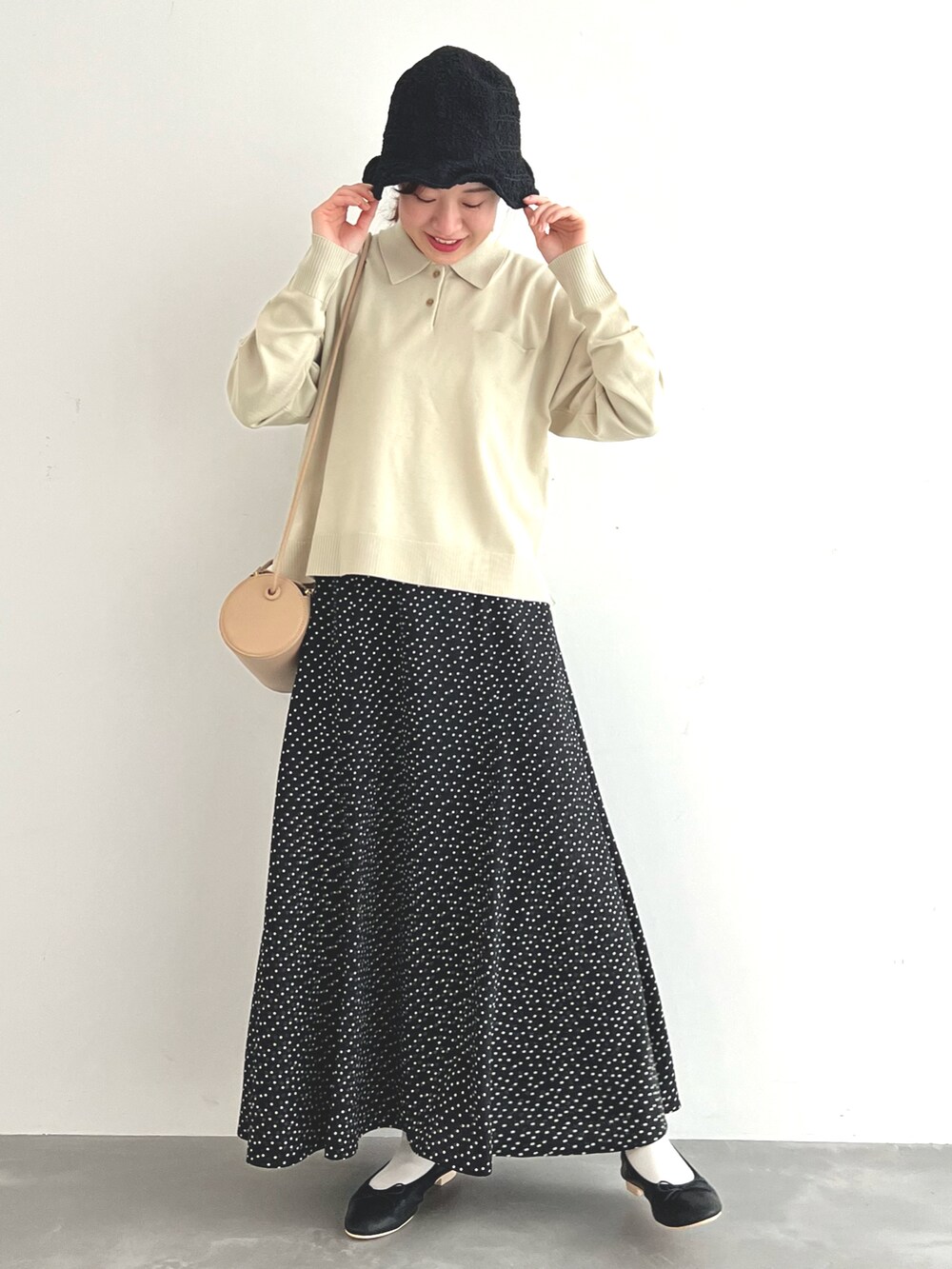 ベージュ系のニット/セーター、ブラック系のスカート、ブラック系のバレエシューズを着用したレディースの春コーディネートの2枚目の写真