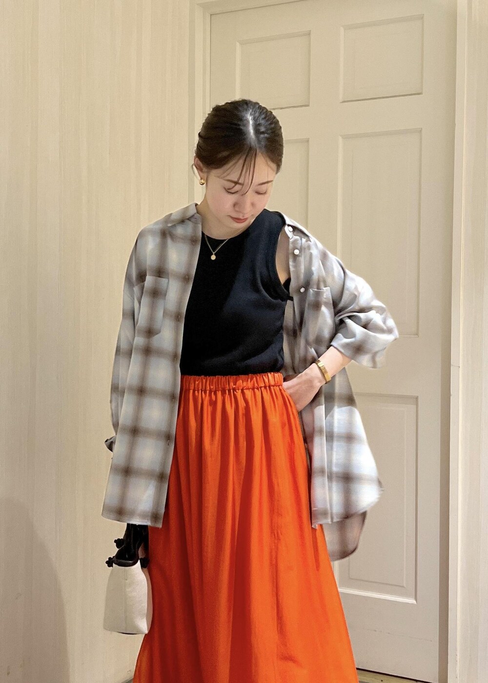 オレンジ系のスカート、ブラック系のタンクトップ、ブラック系のサンダルを着用したレディースの夏コーディネートの7枚目の写真