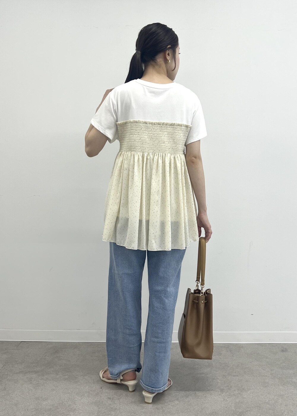 ブルー系のデニムパンツ、ブラウン系のショルダーバッグ、ブラック系のTシャツ/カットソーを着用したレディースの夏コーディネートの3枚目の写真