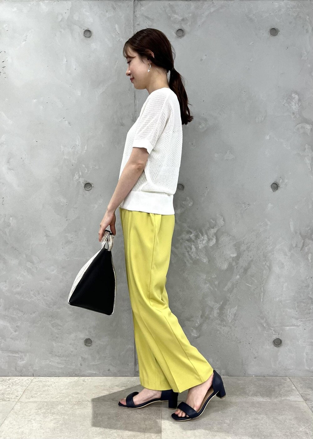 ブラック系のサンダル、イエロー系のスラックス、ブラック系のショルダーバッグを着用したレディースの夏コーディネートの2枚目の写真
