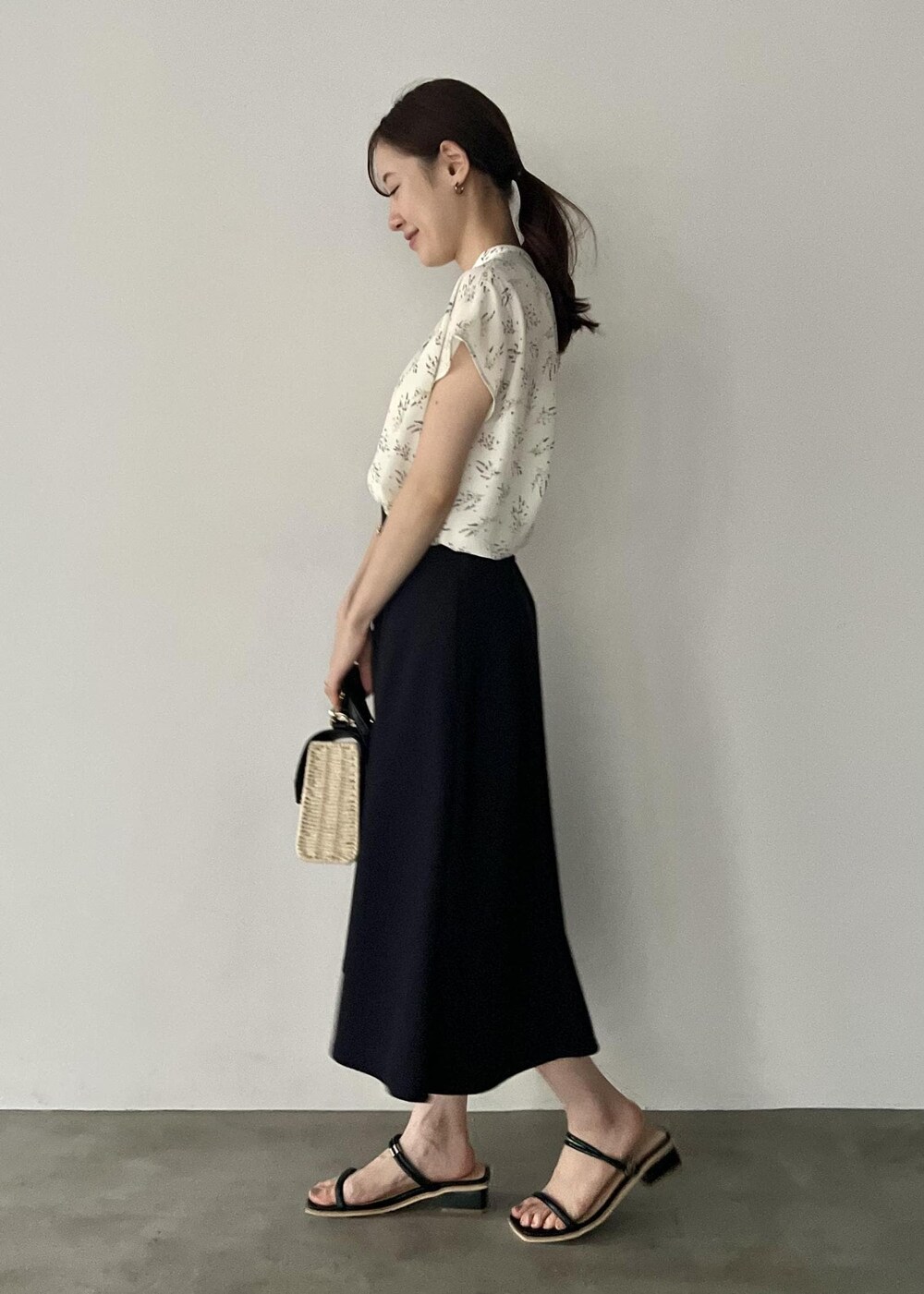 ブラック系のショルダーバッグ、ブラック系のサンダル、ブルー系のスカートを着用したレディースの夏コーディネートの2枚目の写真