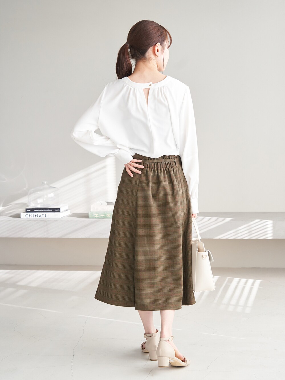 ホワイト系のシャツ/ブラウス、ブラウン系のスカート、ベージュ系のサンダルを着用したレディースの冬コーディネートの3枚目の写真