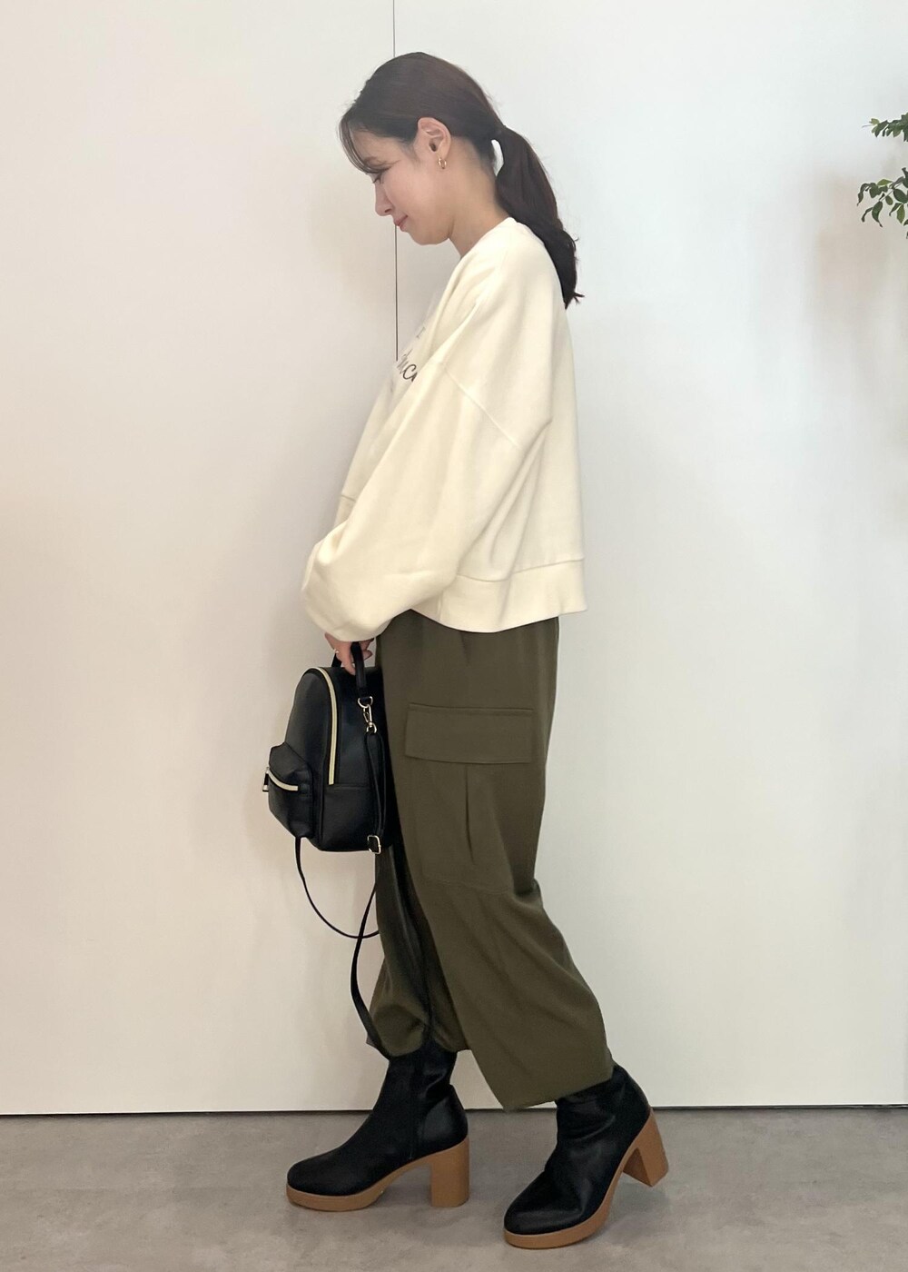 ブラック系のバックパック/リュック、ブラック系のブーツ、ホワイト系のスウェットを着用したレディースの秋コーディネートの2枚目の写真
