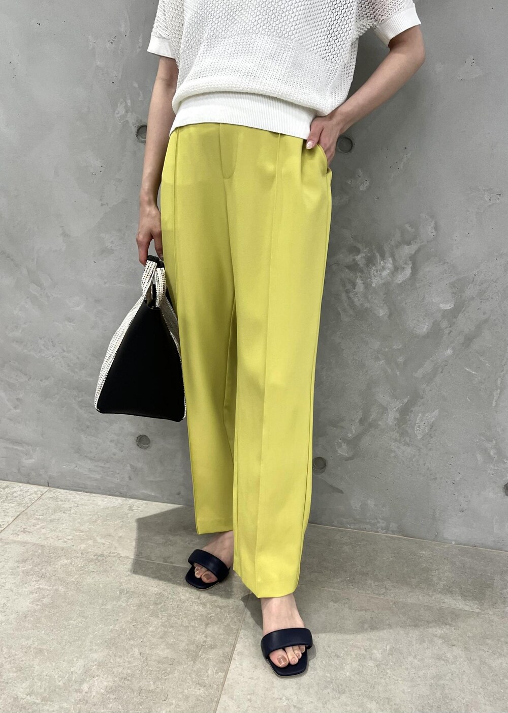 ブラック系のサンダル、イエロー系のスラックス、ブラック系のショルダーバッグを着用したレディースの夏コーディネートの6枚目の写真