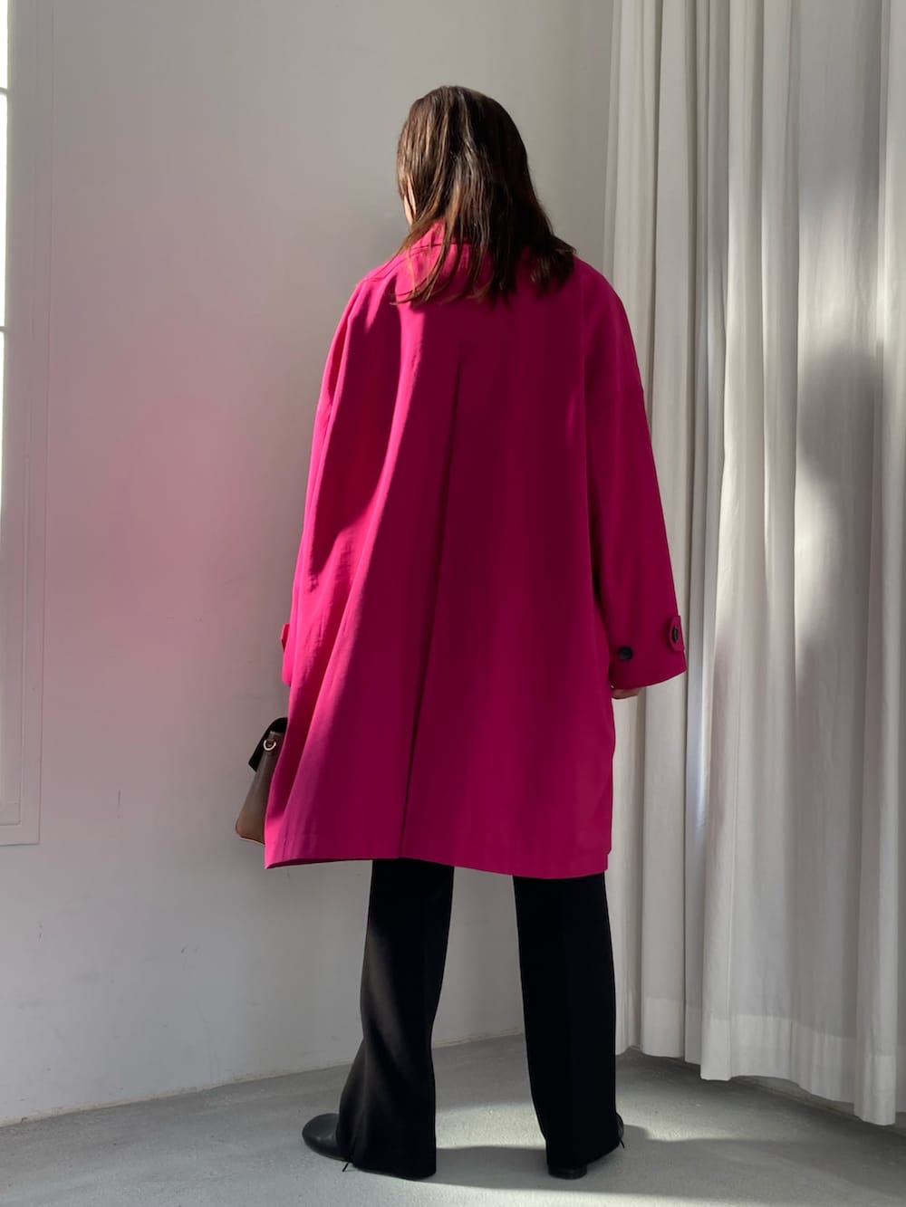 ピンク系のステンカラーコート、ブラウン系のショルダーバッグ、ブラック系のその他パンツを着用したレディースの冬コーディネートの3枚目の写真