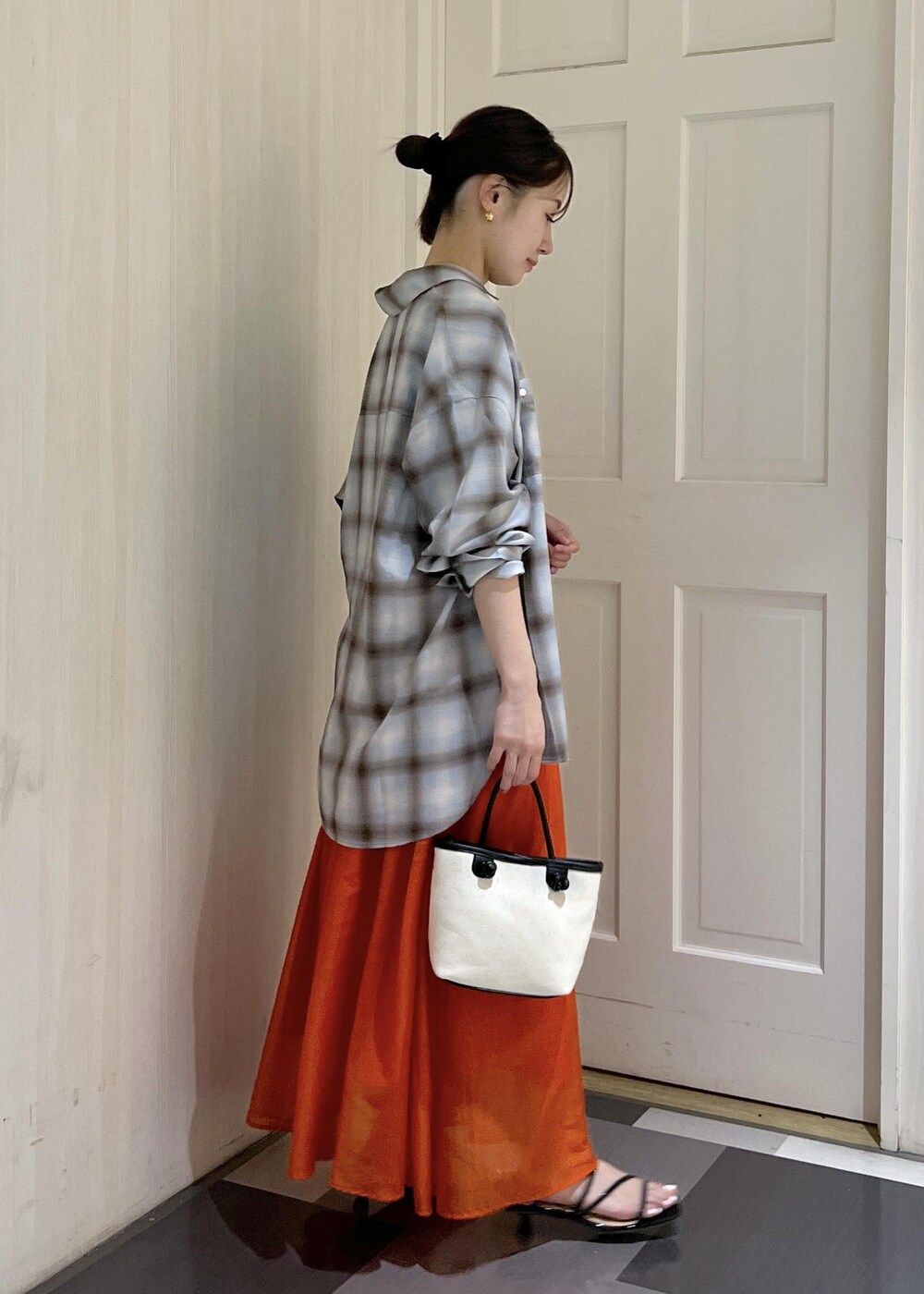 オレンジ系のスカート、ブラック系のタンクトップ、ブラック系のサンダルを着用したレディースの夏コーディネートの3枚目の写真