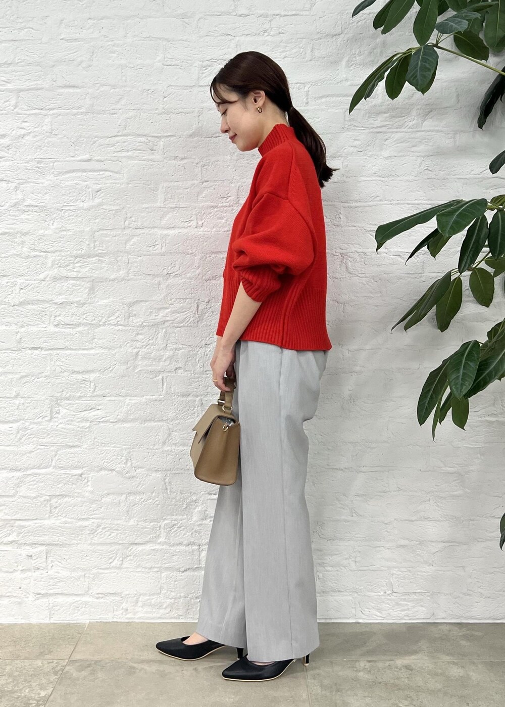 レッド系のニット/セーター、グレー系のその他パンツ、ブラック系のパンプスを着用したレディースの秋コーディネートの2枚目の写真