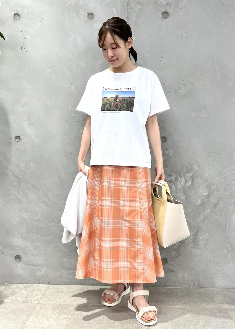 オレンジ系のスカート、グレー系のカーディガン/ボレロ、ホワイト系のTシャツ/カットソーを着用したレディースの春コーディネートの4枚目の写真
