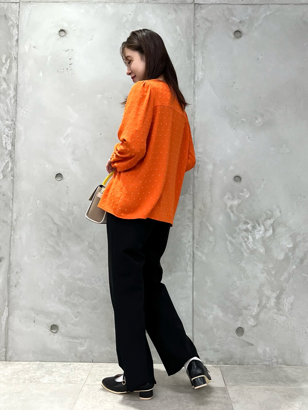 オレンジ系のシャツ/ブラウス、イエロー系のショルダーバッグ、ブラック系のその他パンツを着用したレディースの春コーディネートの2枚目の写真