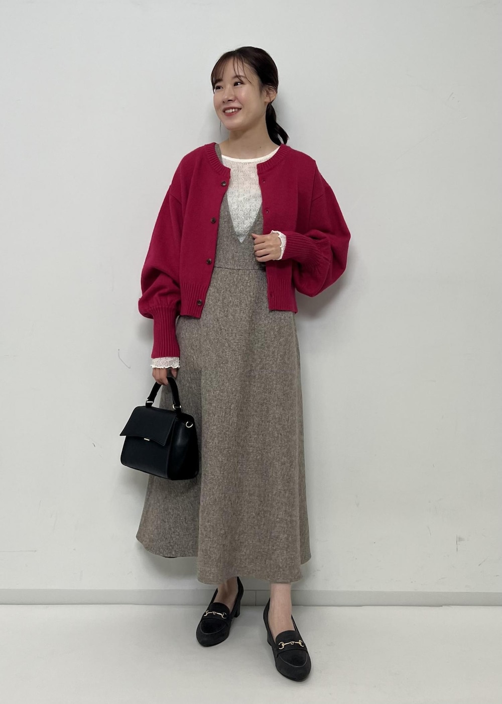 ベージュ系のジャンパースカート、ピンク系のカーディガン/ボレロ、ホワイト系のTシャツ/カットソーを着用したレディースの秋コーディネートの4枚目の写真