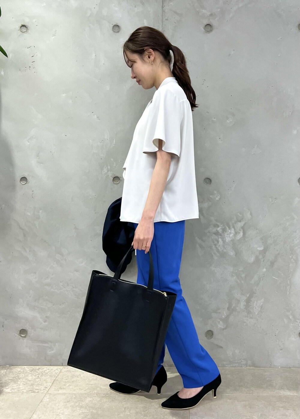 ブラック系のパンプス、ブルー系のスラックス、ブラック系のトートバッグを着用したレディースの春コーディネートの5枚目の写真