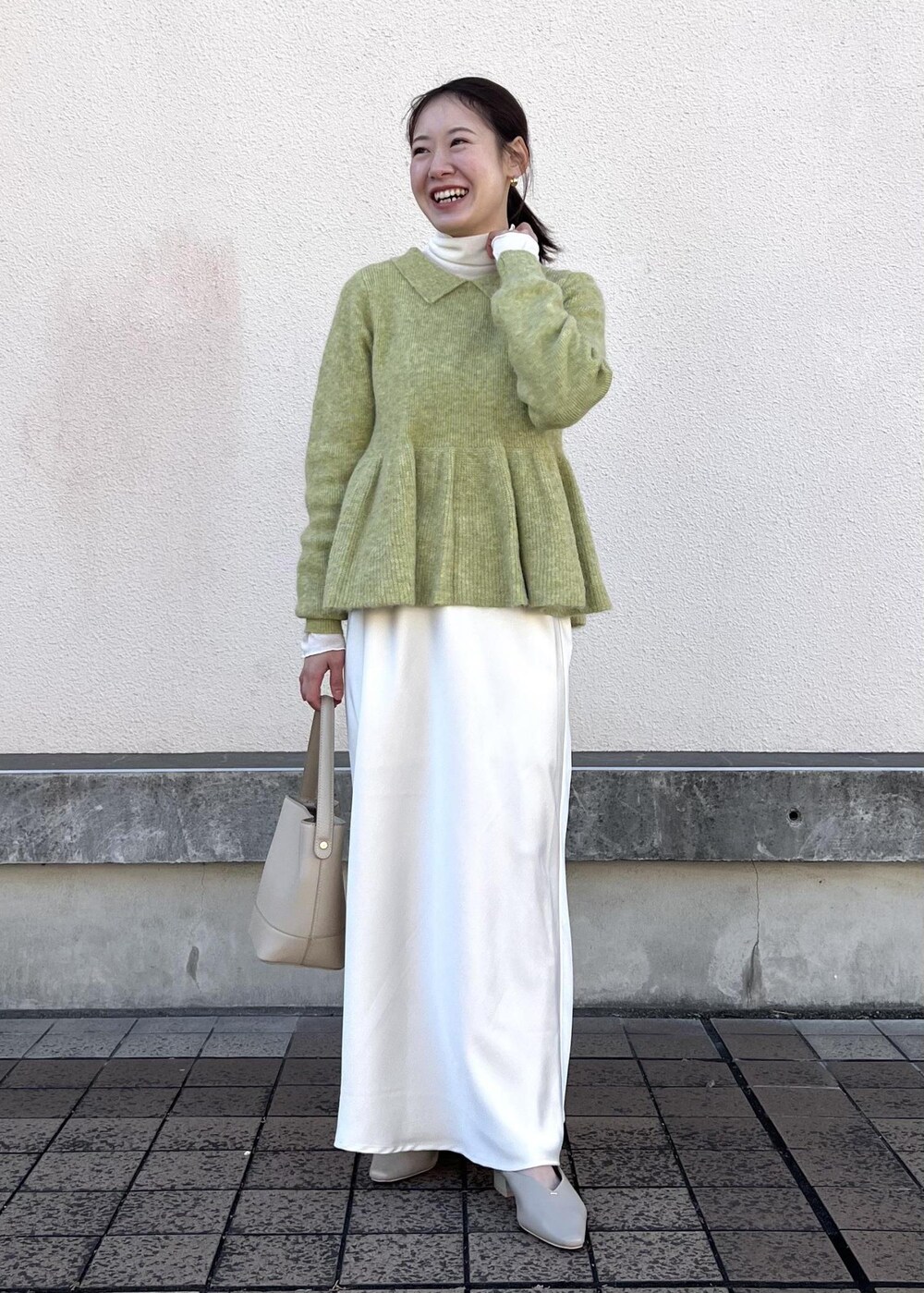 ホワイト系のスカート、グリーン系のニット/セーター、ベージュ系のパンプスを着用したレディースの冬コーディネートの3枚目の写真