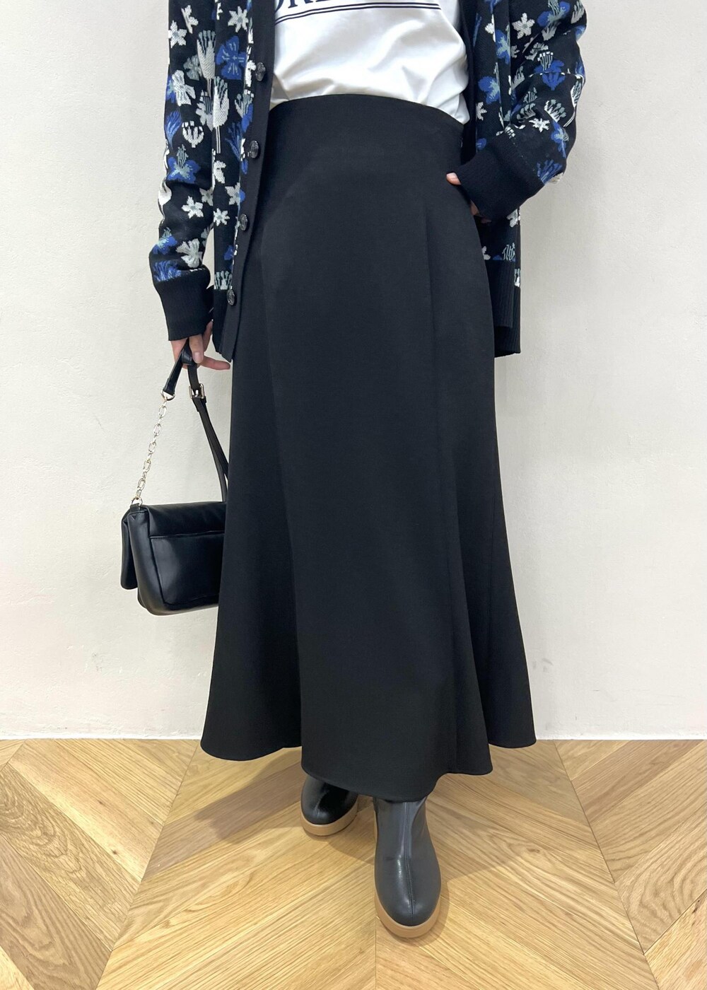 ブラック系のスカート、ホワイト系のTシャツ/カットソー、ブラック系のショルダーバッグを着用したレディースの秋コーディネートの5枚目の写真