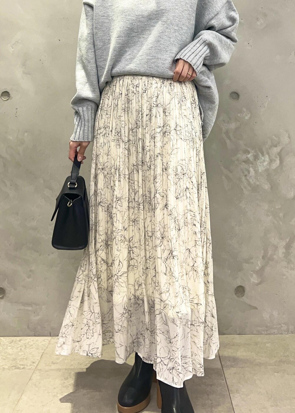 ホワイト系のスカート、グレー系のニット/セーター、ブラック系のショルダーバッグを着用したレディースの冬コーディネートの6枚目の写真