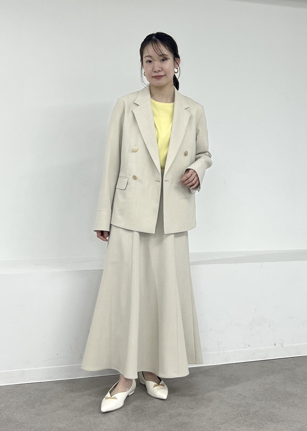 ホワイト系のパンプス、ベージュ系のテーラードジャケット、ベージュ系のスカートを着用したレディースの春コーディネートの3枚目の写真