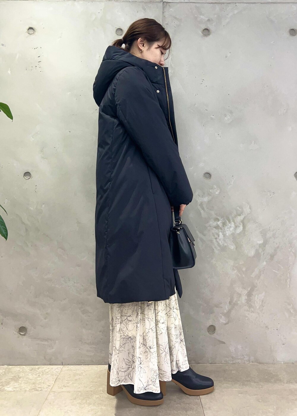 ホワイト系のスカート、グレー系のニット/セーター、ブラック系のショルダーバッグを着用したレディースの冬コーディネートの2枚目の写真