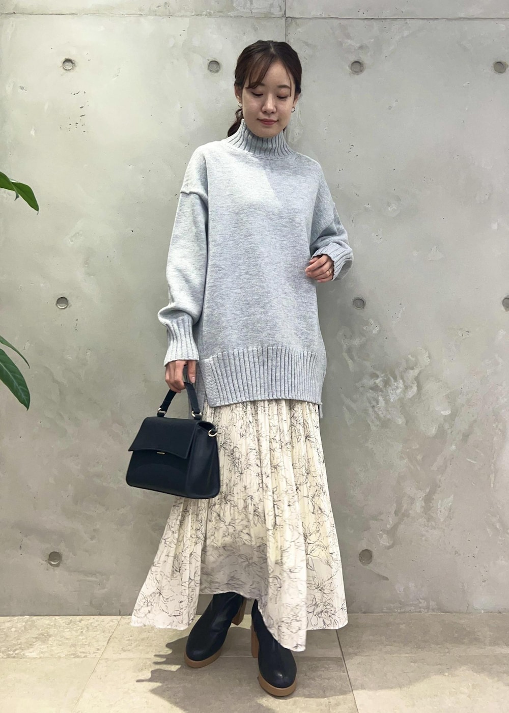 ホワイト系のスカート、グレー系のニット/セーター、ブラック系のショルダーバッグを着用したレディースの冬コーディネートの4枚目の写真