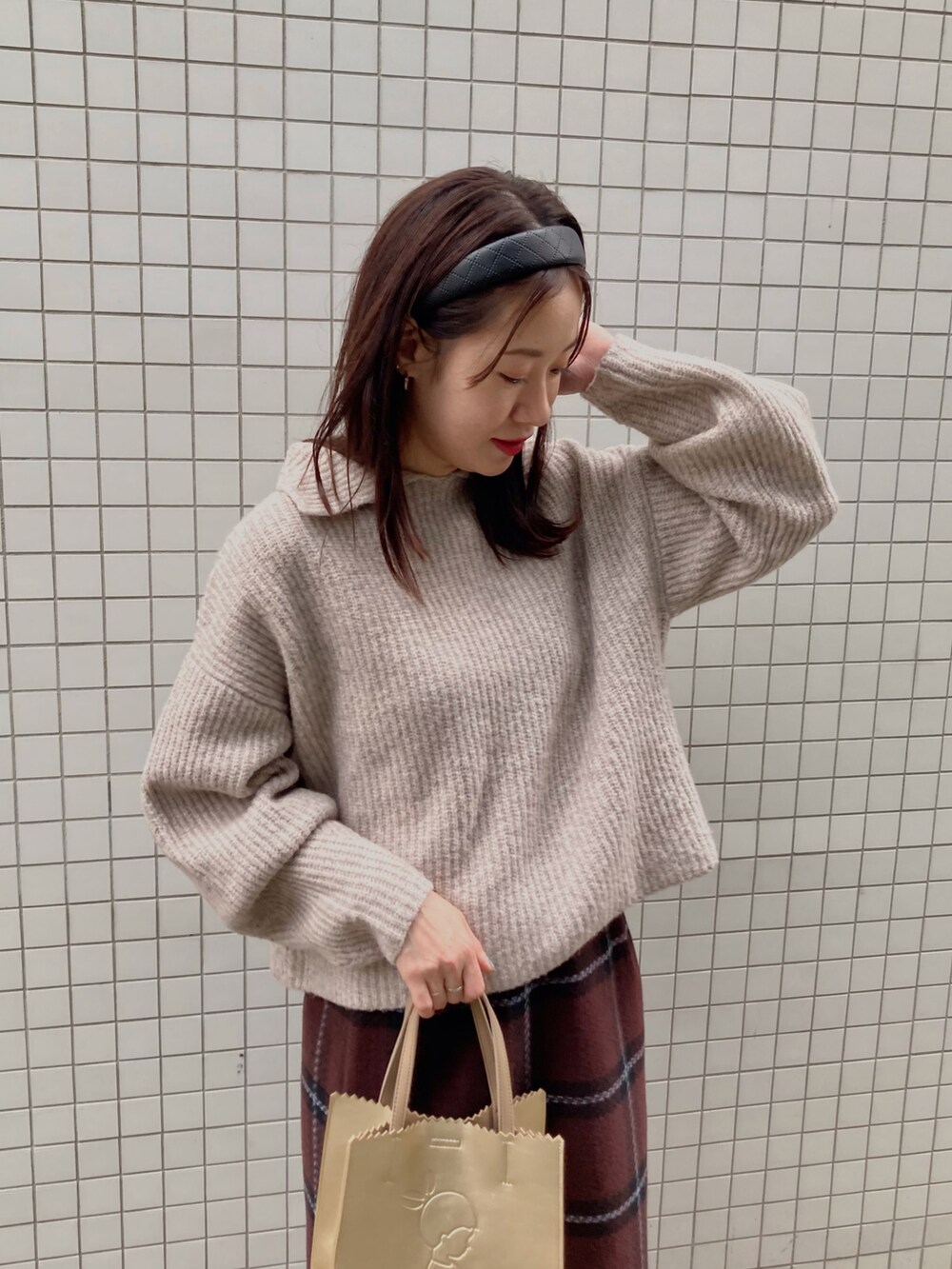 ベージュ系のニット/セーター、ゴールド系のトートバッグ、ブラウン系のブーツを着用したレディースの秋コーディネートの3枚目の写真